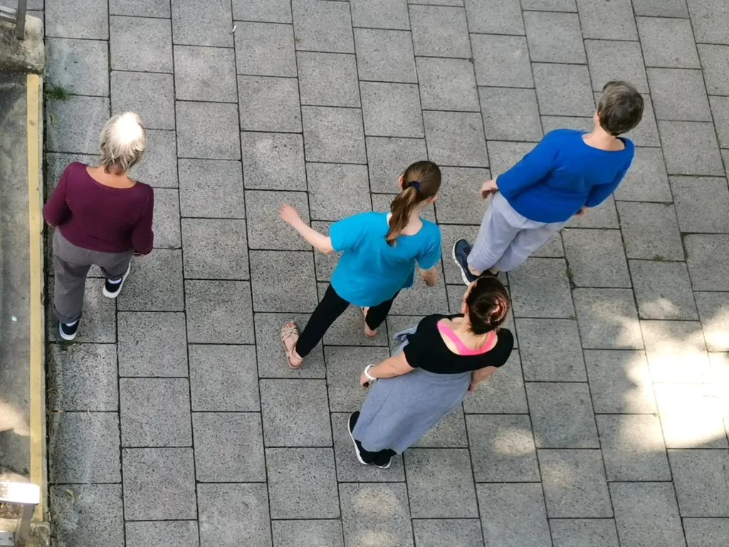 Vier Personen sind von oben zu sehen. Sie bewegen sich auf einem Gehweg.