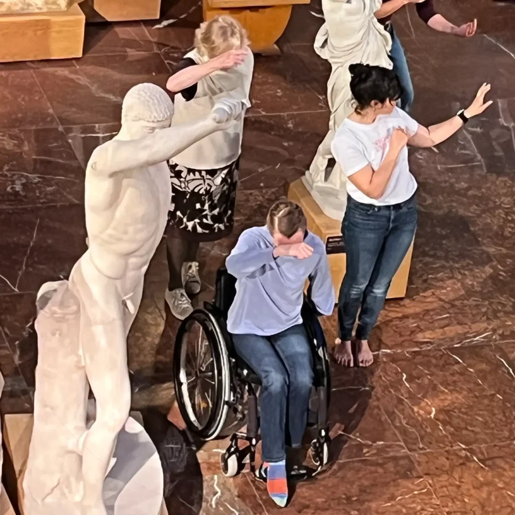 Tanzende imitieren die Pose einer Statue in einem Museum.